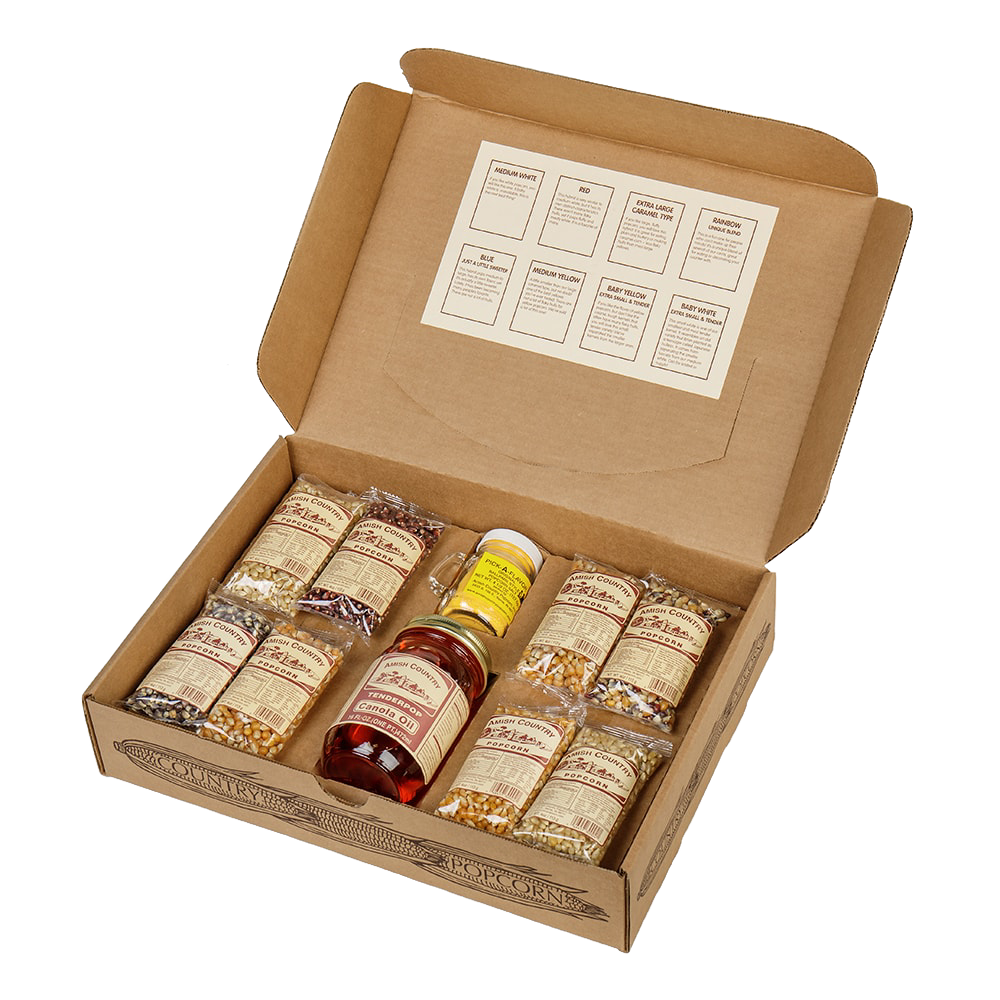 Open cardboard box containing eight small labeled bags of assorted handcrafted popcorn kernels, a bottle of Amish-made seasoning and a jar of syrup, suitable for Kitchen & Food, Snacks and Sweets, USA Made, Amish Made, and Best Sellers collections.