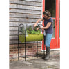 Woman tending to plants in a green fabric raised garden bed with a clear polyethylene greenhouse cover and black metal frame, suitable for patios and small outdoor spaces in Farm, Garden & Tool and Garden Accessories collections.