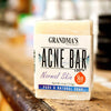 Handcrafted acne soap bar labeled for normal skin and skin-safe formulation, displayed on a rustic wooden surface in Health & Wellness and Soaps collections.
