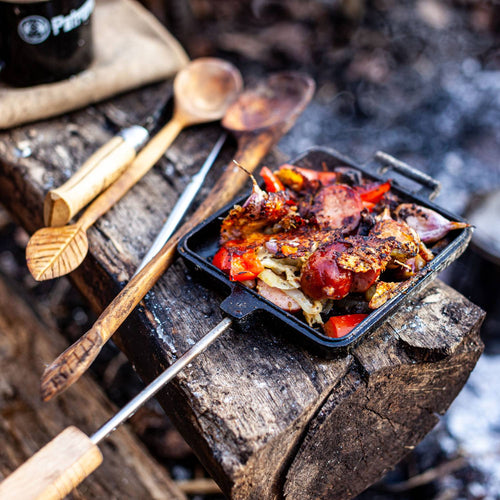Cast iron sandwich iron with wooden handle cooking a flavorful mix of grilled vegetables and meat over a rustic campfire setting, ideal for Farm, Garden & Tool, Camping, Best Sellers, and Promo Eligible collections.