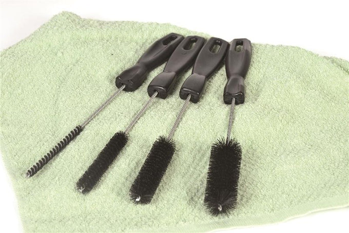 Four different sized cleaning brushes with black handles and stiff bristles arranged on a green towel, perfect for household cleaning tasks in Home & Decor and USA Made collections.