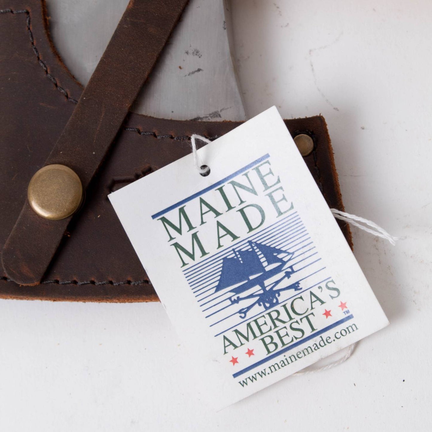 Close-up of a leather sheath with a metal snap button and attached Maine Made tag, highlighting American craftsmanship and quality standards in Farm, Garden & Tool and USA Made collections.