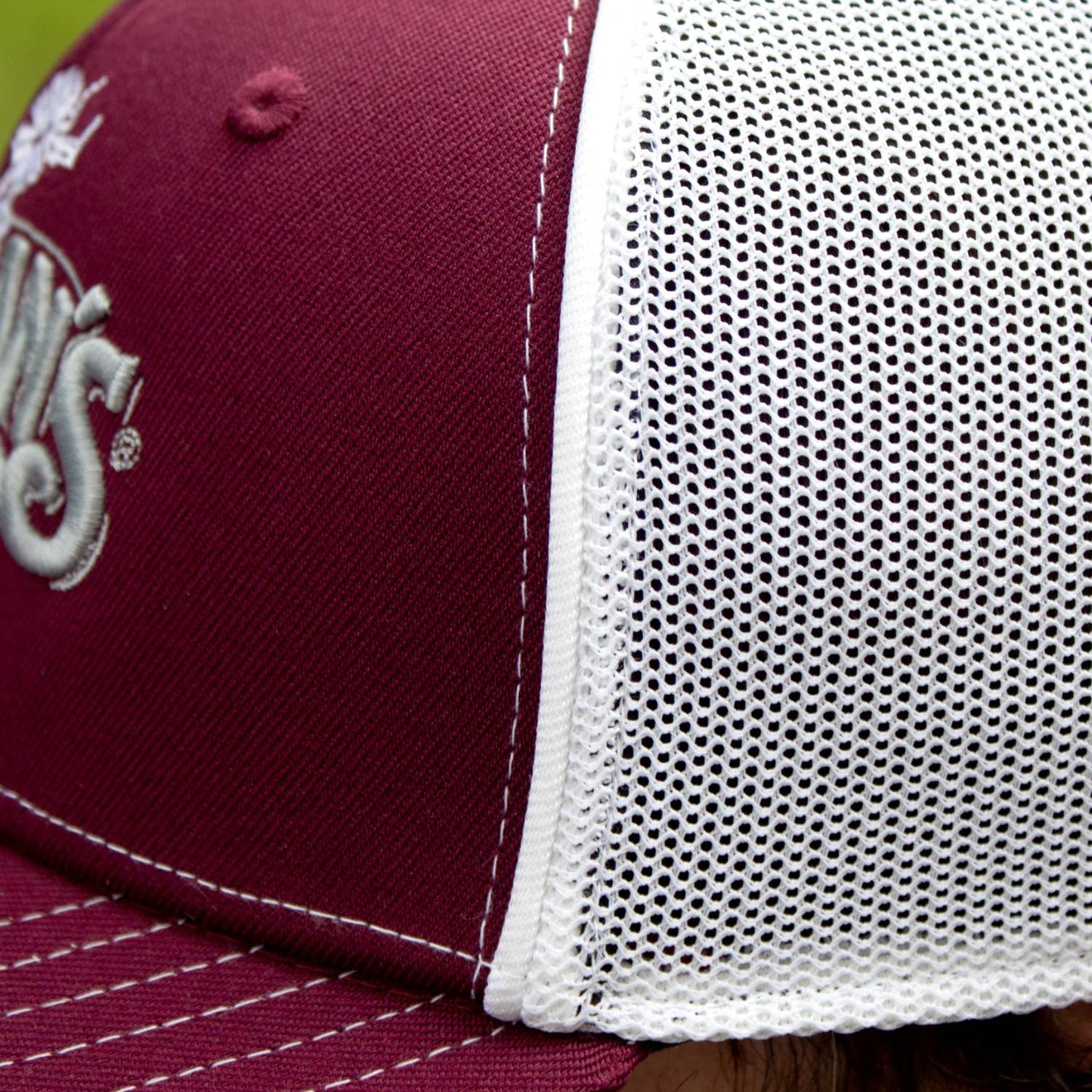 Close-up of a handcrafted trucker hat with a burgundy front panel, white breathable stretch mesh back, detailed embroidery, and white stitching, ideal for Health & Wellness, Clothing and Accessories, Best Sellers, and Promo Eligible collections.