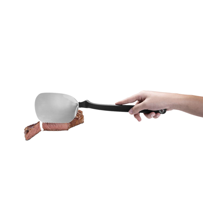 BBQ Chopula stainless steel grill spatula with a black ergonomic handle lifting a sliced piece of steak, suitable for Kitchen & Food, Grilling, and Best Sellers collections.