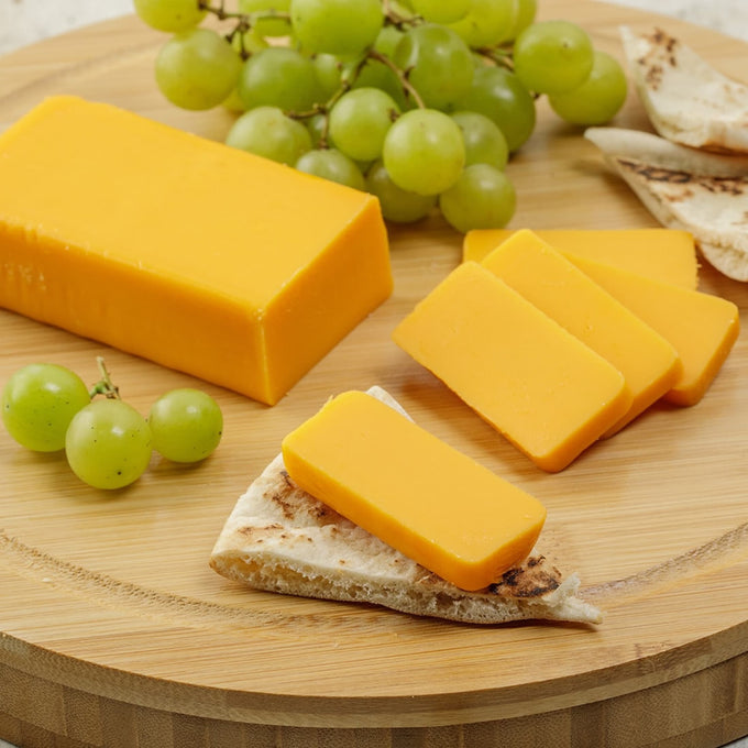 Two 8-ounce handcrafted shelf-stable cheese food blocks, sliced and served on flatbread with green grapes on a round board, ideal for Kitchen & Food, Pantry, Snacks and Sweets, USA Made, and Best Sellers collections.