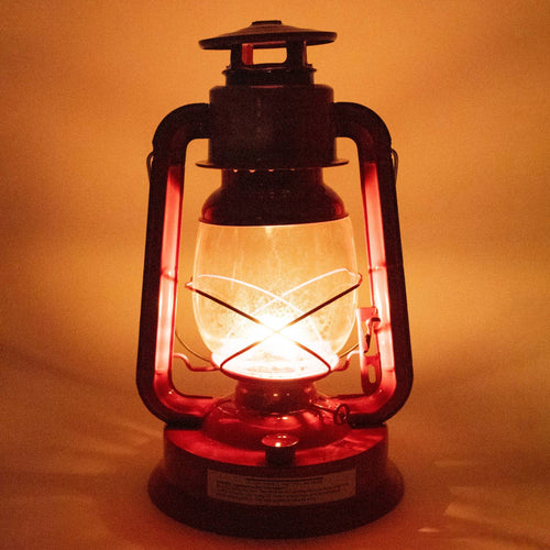 Handcrafted red metal lantern with glowing flame inside frosted glass globe, designed for outdoor use in camping, pest control, farm, garden, and emergency lighting collections.