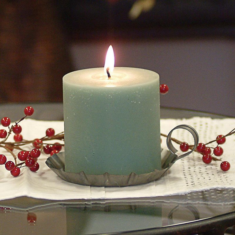 Lit green bayberry pillar candle with a smooth surface resting in a vintage metal holder, surrounded by red holiday berries, part of Kitchen & Food and USA Made collections.