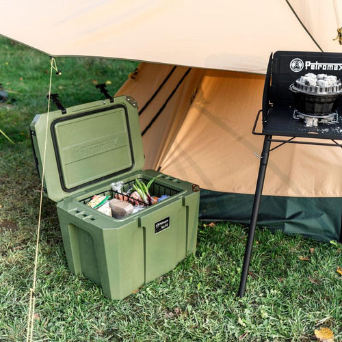 Olive green cooler box with insulated interior open and filled with food, placed on grass near a tan camping tent and portable stove, ideal for Farm, Garden & Tool, Camping, and Best Sellers collections.