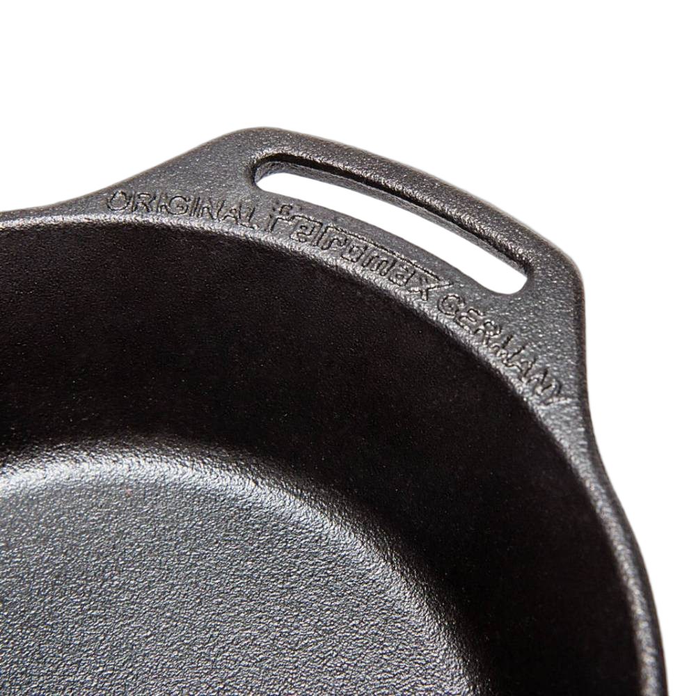 Close-up of a high-quality cast iron skillet featuring two side handles and embossed branding, ideal for cooking over open fire or kitchen use in Farm, Garden & Tool and Cookware collections.