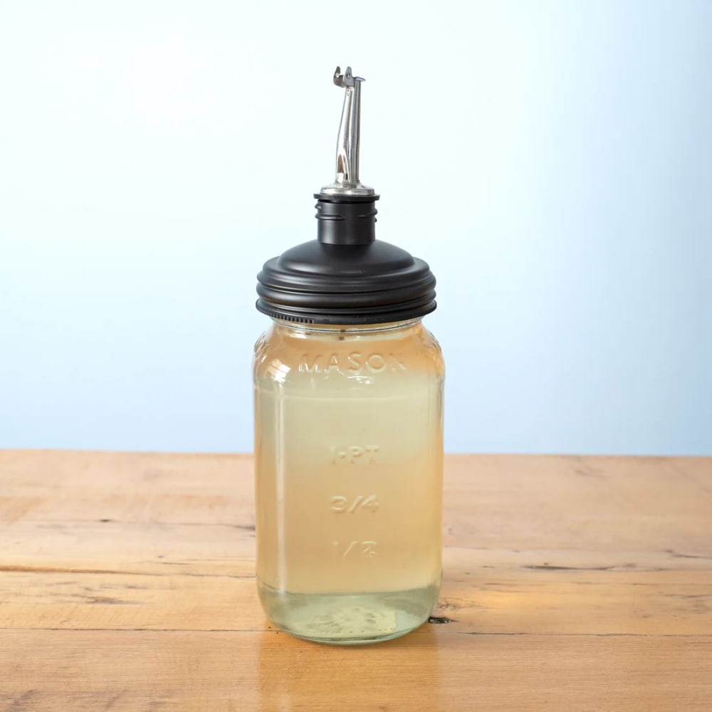 Clear liquid-filled regular-mouth Mason jar fitted with a black reCAP pour spout lid featuring a stainless steel tap, ideal for Kitchen Gadgets, Kitchen & Food, USA Made, and Best Sellers collections.