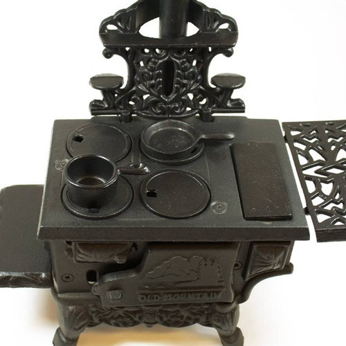 Miniature cast iron wood cook stove replica with intricate detailing, working oven doors, removable lids, and small pots and skillet, perfect for indoor play and children's toys collections.