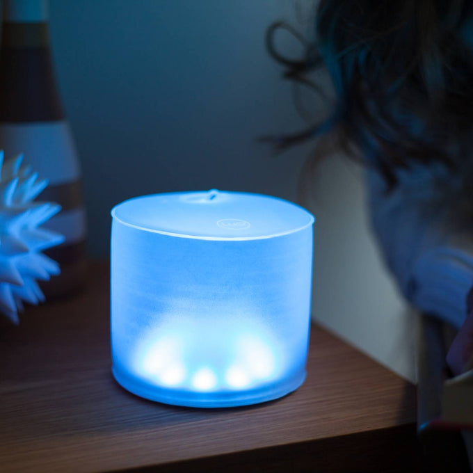 Soft blue glowing Luci Color Essence solar light with a compact, inflatable design, perfect for eco-friendly use in camping, farm, garden, and emergency lighting needs.
