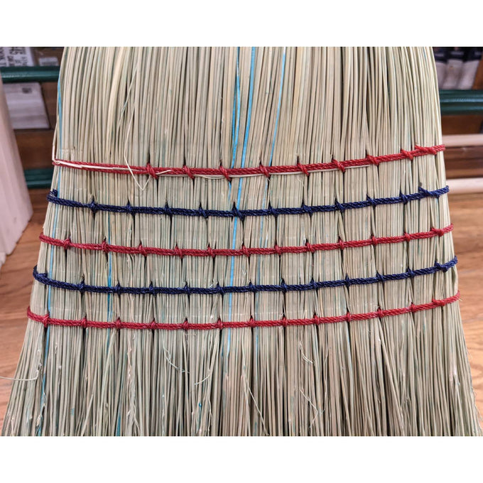 Close-up of a handcrafted large corn broom with tightly bound natural corn straw bristles featuring red and blue stitching, Amish made in the USA for farm, garden, and household cleaning.