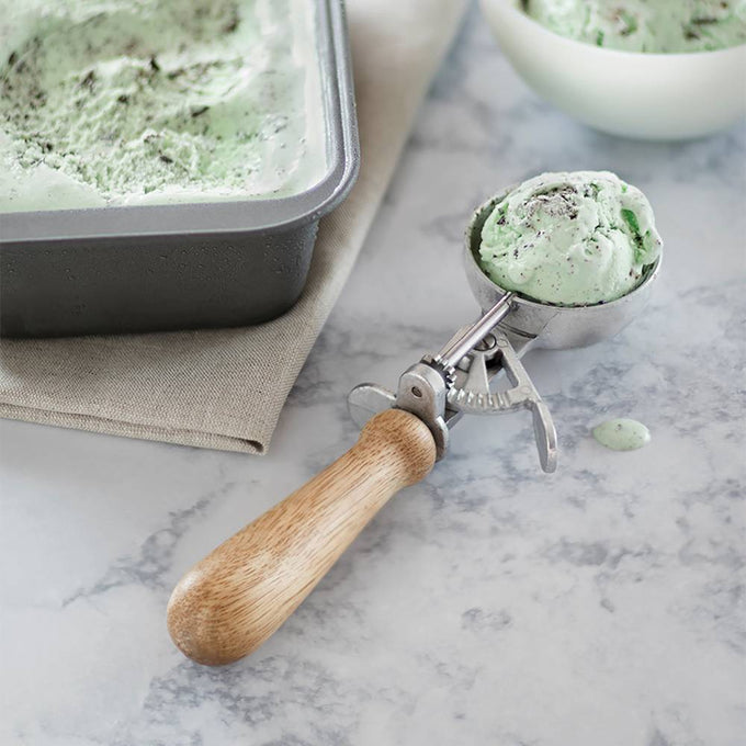 Handcrafted ice cream scoop with a smooth wooden handle and stainless steel scoop releasing mint chocolate chip ice cream, ideal for Kitchen & Food and Specialty Equipment collections.