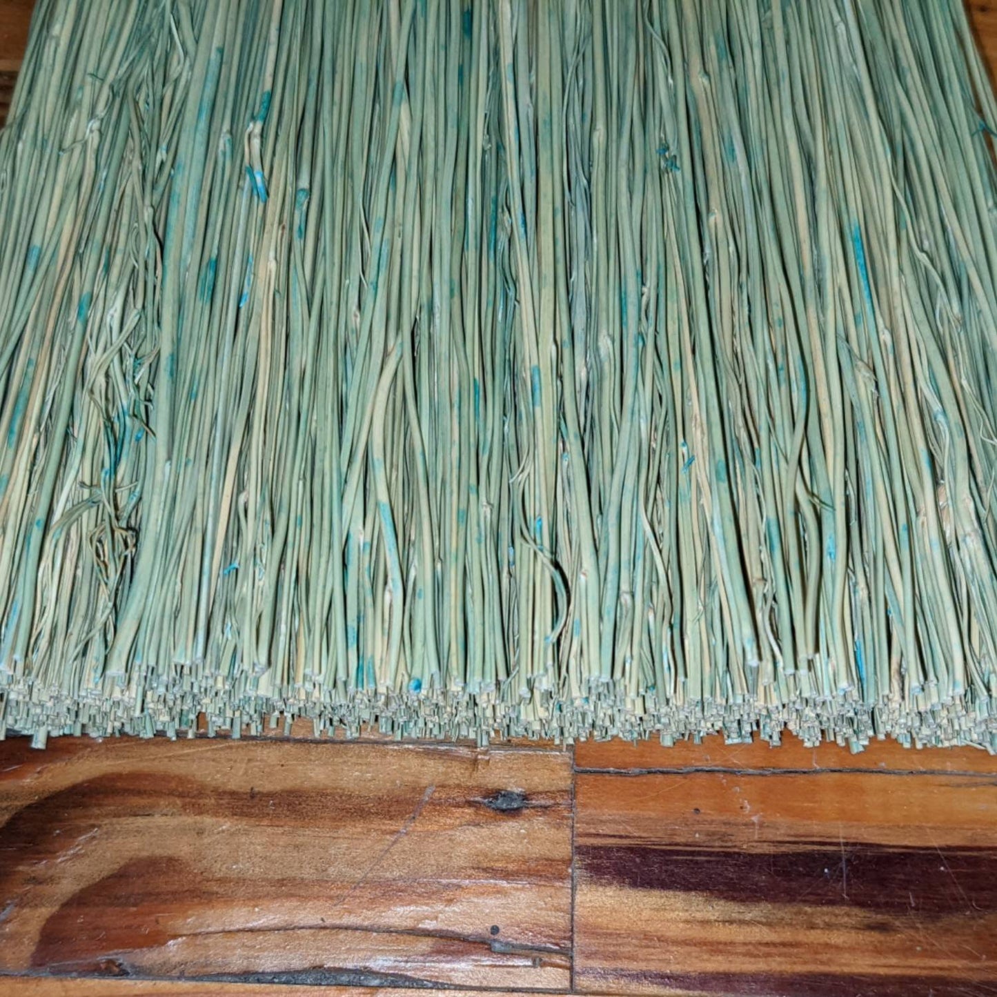 Close-up of tightly bundled natural corn straw bristles with subtle blue accents on a handcrafted Amish-made broom, resting on a wooden surface, featured in Home & Decor and Household Cleaning collections.