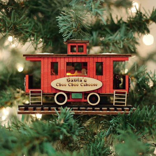 Handmade red caboose ornament with detailed craftsmanship and built-in amber light, hanging on a Christmas tree, perfect for Home & Decor and Holiday Decor collections.