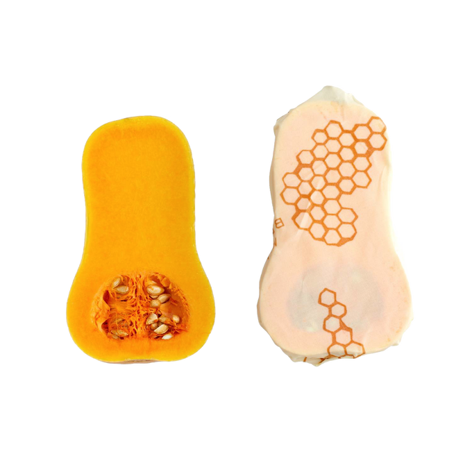 Handmade large muslin food wrap with beeswax coating featuring honeycomb pattern, shown wrapped around a halved butternut squash, ideal for Kitchen & Food and Storage collections.