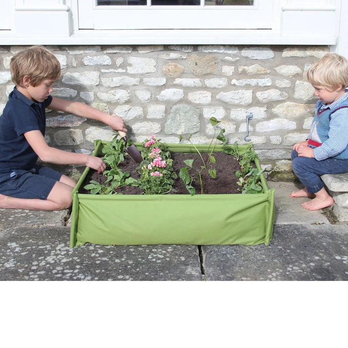 Two children engaged with a green fabric raised garden bed containing young plants and flowers, perfect for introducing gardening in Farm, Garden & Tool, Children's Toys, and Outdoor Play collections.