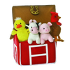 Soft plush duck, cow, pig, and rooster toys sitting inside a bright red fabric barn with a horseshoe detail, designed for indoor play and children's toy collections.