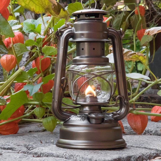 Handcrafted brown galvanized oil lantern with a clear thermal heat-resistant glass globe and sturdy metal frame, ideal for camping, emergency supplies, and outdoor lighting.