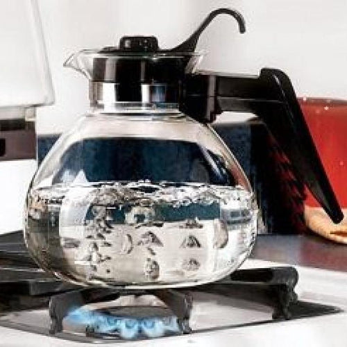 Clear borosilicate glass teakettle with black handle and stainless steel band boiling on a gas stove, perfect for Kitchen & Food, Brewing Coffee and Tea, Best Sellers, and Promo Eligible collections.
