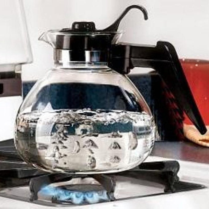 Clear borosilicate glass teakettle with black handle and stainless steel band boiling on a gas stove, perfect for Kitchen & Food, Brewing Coffee and Tea, Best Sellers, and Promo Eligible collections.