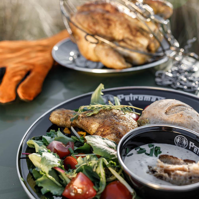 Black enamel plate with Petromax logo, holding grilled chicken, fresh salad, creamy dip, and a bread roll, perfect for camping, kitchen, and outdoor dining in Farm, Garden & Tool collections.