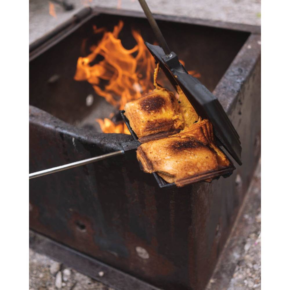 Handcrafted cast iron double sandwich iron with removable handles cooking over an open flame, designed for easy cleaning and durable outdoor use in Farm, Garden & Tool and Camping collections.