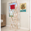 Handcrafted Amish made adjustable wooden clothes dryer standing in a bright laundry room with towels draped over its multiple drying bars, highlighting space-saving design.