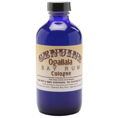 Blue glass bottle of handcrafted cologne made in USA with vintage-style beige label for health and wellness and grooming collections, featuring a manly bay rum scent.