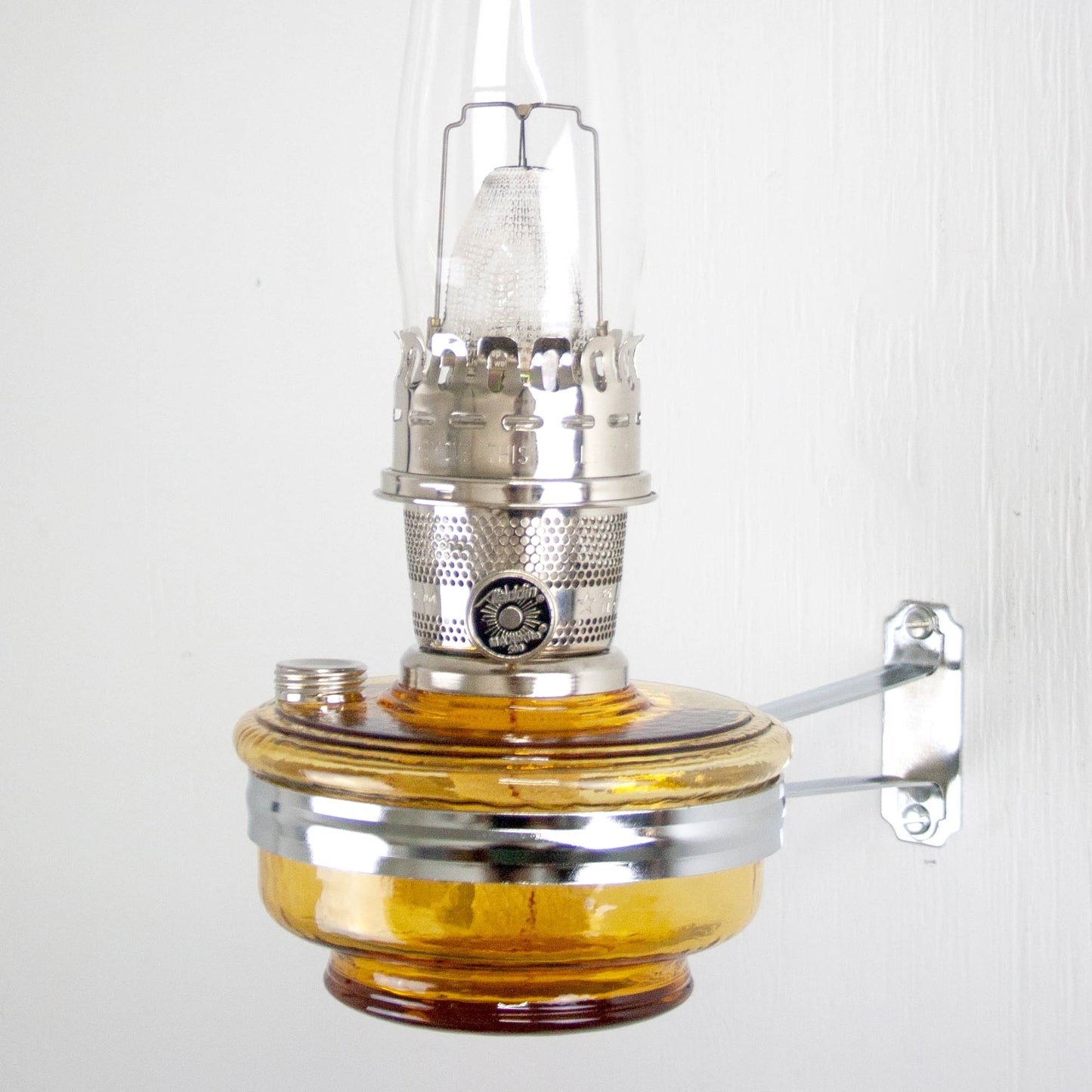 Wall-mounted amber glass oil lamp with polished metal burner and adjustable wick, handcrafted and ideal for Farm, Garden & Tool, Lamps & Lighting, Emergency Supplies, and Best Sellers collections.