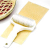 White plastic lattice cutter roller creating evenly spaced strips on pastry dough next to a partially visible pie with fruit filling, suitable for Kitchen & Food and Baking Supplies collections.