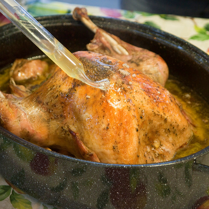 Handcrafted classic graniteware roaster in speckled black enamel-on-steel, shown with a golden roast chicken being basted, ideal for Kitchen & Food, Cookware, Pots and Pans, and Best Sellers collections.