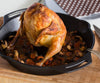Seasoned whole chicken roasted upright in a cast iron pan surrounded by sautéed mushrooms and carrots, showcased for Kitchen & Food, Cookware, Cast Iron, and Best Sellers collections.