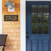 Custom modern aged bronze address plaque with gold numbers mounted on natural wood shingle siding near a blue front door, part of Home & Decor and USA Made collections.