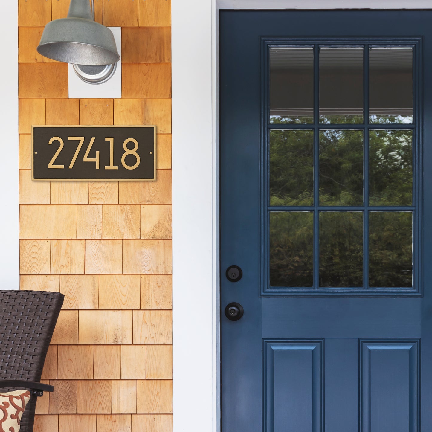 Custom modern aged bronze address plaque with gold numbers mounted on natural wood shingle siding near a blue front door, part of Home & Decor and USA Made collections.