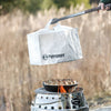 Light-colored heat-resistant convection lid held by tongs above a dutch oven with baked food on an outdoor camping stove, suitable for Farm, Garden & Tool and Camping collections.