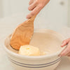Handcrafted American hard maple paddle with a curved, extra-wide design for easier butter handling, shown pressing homemade butter in a ceramic mixing bowl, ideal for Kitchen & Food and Specialty Equipment collections.