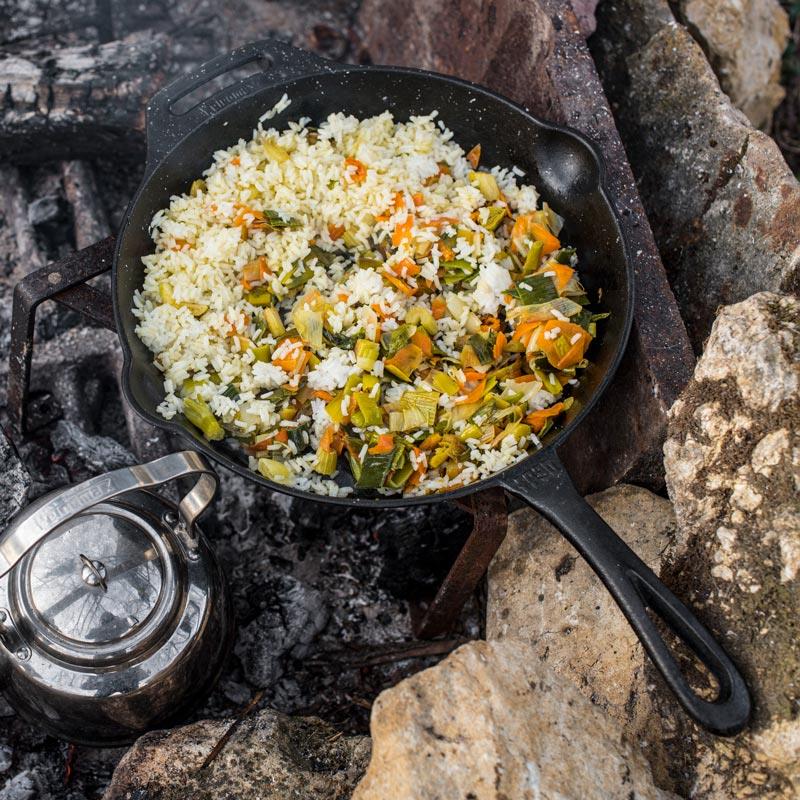 Cast iron skillet with long handle cooking seasoned rice and mixed vegetables over hot coals, perfect for Farm, Garden & Tool, Kitchen & Food, Camping, Cookware, Cast Iron, and Best Sellers collections.