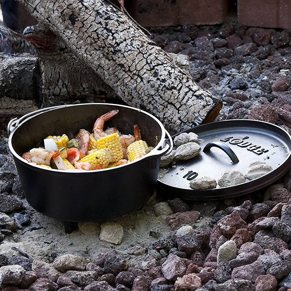 Handcrafted cast iron camp Dutch oven with built-in legs cooking shrimp, corn, and potatoes over hot charcoal, featured in Camping, Cast Iron, USA Made, and Best Sellers collections.