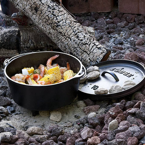 Handcrafted cast iron camp Dutch oven with built-in legs cooking shrimp, corn, and potatoes over hot charcoal, featured in Camping, Cast Iron, USA Made, and Best Sellers collections.