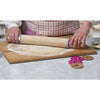 Hands using a beechwood adjustable rolling pin with removable discs to roll out dough on a floured wooden board, part of kitchen and baking supplies collections.