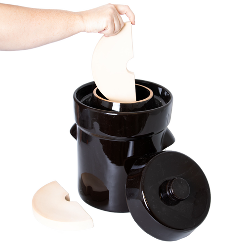 Handcrafted dark stoneware fermenting crock with lid removed, shown with ceramic weights being placed inside, ideal for Kitchen & Food, Food Preservation, Fermenting and Pickling, Best Sellers, and Promo Eligible collections.