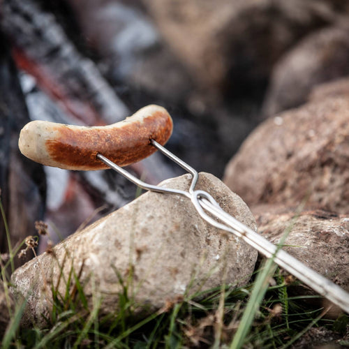 Handcrafted adjustable skewer with wooden handle holding a sausage over a glowing campfire, ideal for relaxing outdoor cooking in Farm, Garden & Tool, Camping, Best Sellers, and Promo Eligible collections.