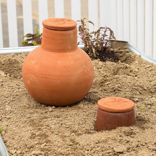 Unglazed terra cotta irrigation pots buried in soil for slow water release, handcrafted and ideal for conserving water in small garden beds and containers, featured in Farm, Garden & Tool and Garden Accessories collections.