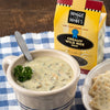 Creamy wild rice soup served in a ceramic bowl with a spoon and fresh parsley garnish, accompanied by crackers and packaged dry soup mix, perfect for Kitchen & Food, Food, Dry Goods and Mixes, Soups, USA Made, Best Sellers, Promo Eligible collections.