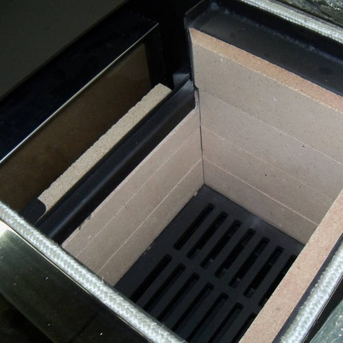 Interior view of a Concept 2 Mini Air Wood Cookstove showing the firebox lined with heat-resistant bricks and a metal grate, designed for efficient wood burning and cooking.