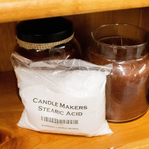Clear plastic bag containing white stearic acid flakes for enhancing candle strength, shown on a wooden shelf with glass jars in Health & Wellness, Candlemaking Supplies, and Soaps and Soapmaking collections.