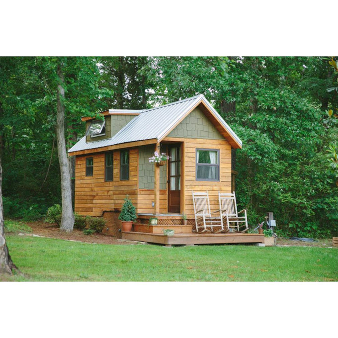 Cozy handcrafted tiny house with wood siding and metal roof, featuring a small porch with two rocking chairs, surrounded by lush green trees in a serene outdoor setting, ideal for Home and Garden How-To Books and Best Sellers collections.