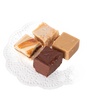 Four handcrafted creamy fudge squares in assorted flavors arranged on a white decorative paper doily, featured in Kitchen & Food and USA Made snack collections.